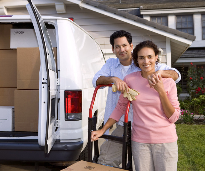 Couple standing behind a van loaded with boxes