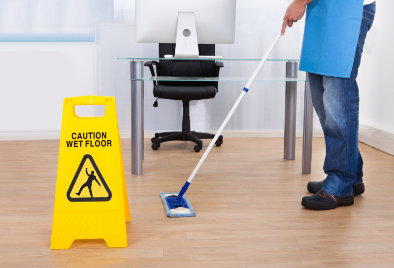 Man mopping the floor with and a wet floor sign